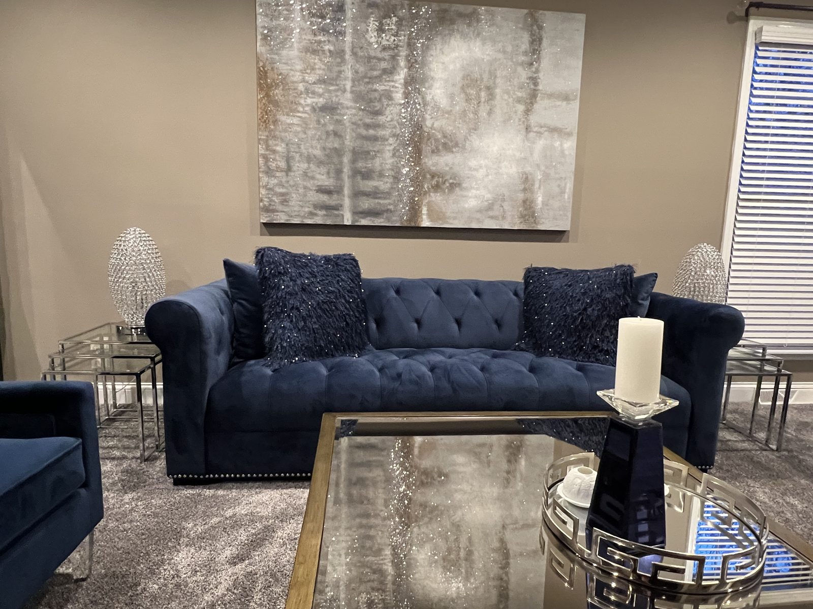 Navy tufted sofa with mirrored and glass accent tables